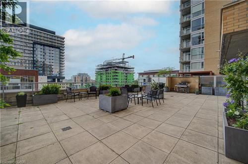 Expansive outdoor terrace featuring large format paver flooring, a perimeter railing, and integrated planter boxes with shrubbery - 191 King Street S Unit# 607, Waterloo, ON 