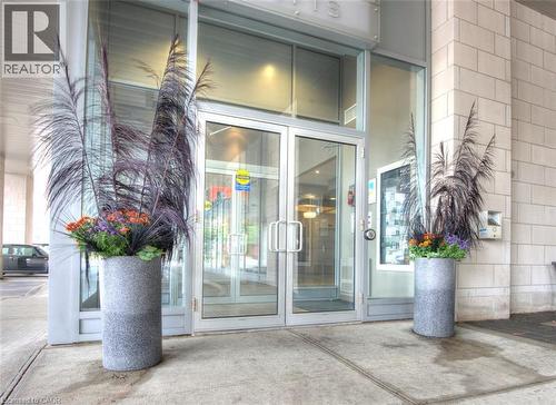 Building entrance with glass double doors, aluminum framing, and concrete exterior - 191 King Street S Unit# 607, Waterloo, ON 
