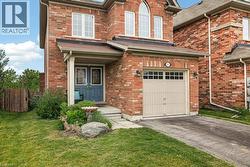 Brick facade residence featuring a covered front entry with double doors, an integrated single-car garage, multiple upper-level windows, and a landscaped front yard with a stone accent - 