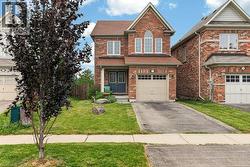 Traditional brick facade residence featuring an arched window, a two-car garage, and a manicured front lawn - 