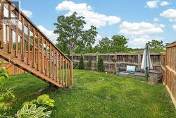 Expansive backyard featuring a manicured lawn, a full wood privacy fence, and mature trees providing natural screening - 