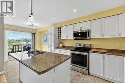 Kitchen featuring an island with double basin sink, white cabinetry, integrated wine rack, stainless steel appliances, and sliding glass doors to outdoor space - 