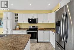 Kitchen featuring white cabinetry, integrated wine rack, and a full suite of stainless steel appliances - 
