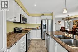 Kitchen featuring white cabinetry, stainless steel appliances, stone-look countertops, and tile flooring - 