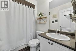 Full bathroom featuring a white vanity with an oval undermount sink, dark countertop, and dark floor tiles - 