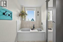 Soaking tub with a tiled surround, a chrome tub filler, and a window above - 