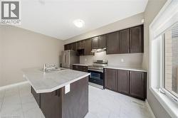 The kitchen features a functional island with a double sink, dark wood cabinetry, stainless steel appliances, and a window providing natural light - 