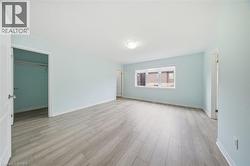 This room features light-colored plank flooring, light blue walls, and a window providing natural light - 
