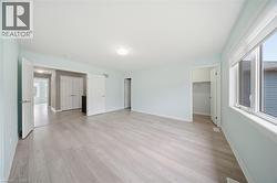 Spacious room featuring light-toned flooring, light blue walls, and a large window providing natural light - 