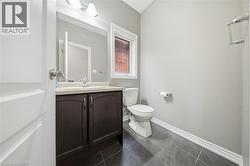 Bathroom featuring a dark wood vanity with a white countertop, a mirror, and a window providing natural light - 