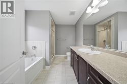 Bathroom featuring a bathtub, a shower with a glass enclosure, a vanity with a single sink, and a large mirror - 