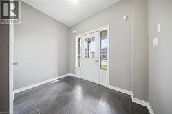 Entryway featuring dark gray tiled flooring and a white front door with glass panes - 