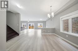 Spacious interior featuring light-colored flooring, a modern chandelier, and large windows providing natural light - 