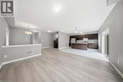 Bright living space featuring light-colored flooring, neutral wall tones, and a view of the kitchen area - 