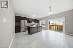 The kitchen features dark wood cabinetry, a stainless steel refrigerator, and a kitchen island - 