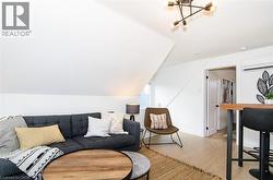 Attic space featuring sloped ceilings, light wood-finish flooring, and a modern multi-directional ceiling light fixture - 