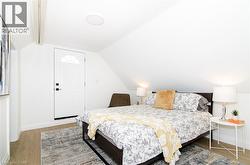 Bright room featuring an arched paneled door, sloped ceiling, wood-finish flooring, and recessed lighting - 