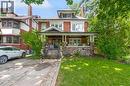 Traditional red brick residence featuring a stone-clad porch foundation, a covered front porch, a gabled entrance, mature perimeter landscaping, and a paved driveway - 110 Melrose Avenue S, Hamilton, ON 