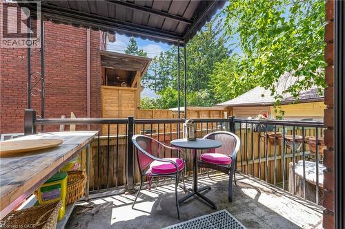 Covered outdoor patio area featuring a concrete surface, black metal railings, and a built-in wood-finish counter - 110 Melrose Avenue S, Hamilton, ON 