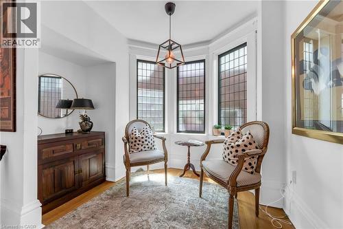 Bay window alcove featuring leaded glass windows, wood-finish flooring, a contemporary ceiling fixture, and a built-in wall niche - 110 Melrose Avenue S, Hamilton, ON 