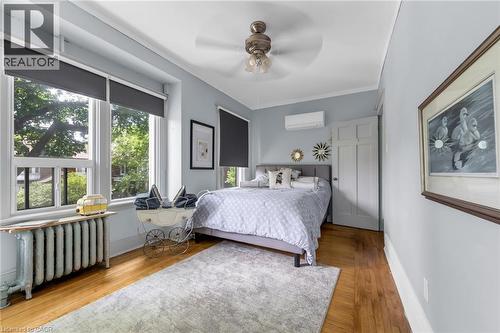 Wood-finish flooring with a radiator beneath a large window - 110 Melrose Avenue S, Hamilton, ON 