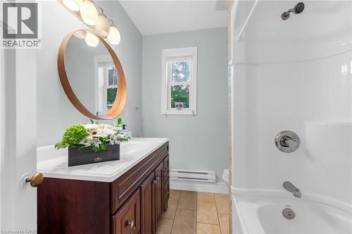 Bathroom featuring a dark wood-finish vanity with a white countertop, an undermount sink, and a circular mirror with a light wood-finish frame - 110 Melrose Avenue S, Hamilton, ON 