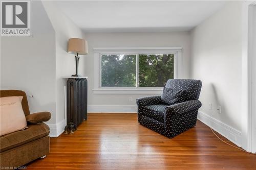 Light-filled room featuring wood-finish flooring, white baseboards, and a large window with white trim - 110 Melrose Avenue S, Hamilton, ON 