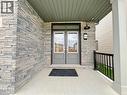 Stone veneer exterior with a covered porch featuring dual entry doors with transom window, black outdoor lighting, and a black metal railing - 66 Aviron Crescent, Welland, ON 