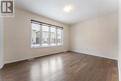 Spare room featuring dark wood-style floors, visible vents, and baseboards - 