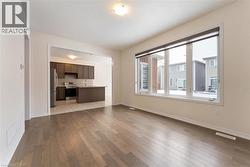 Unfurnished living room featuring wood finished floors, visible vents, and baseboards - 