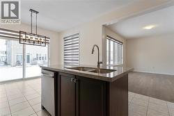 Kitchen featuring light tile patterned floors, stone countertops, dishwasher, open floor plan, and a sink - 