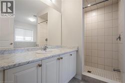 Full bath featuring visible vents, a tile shower, and vanity - 