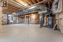 Unfinished below grade area featuring a sink, heating unit, electric panel, and gas water heater - 