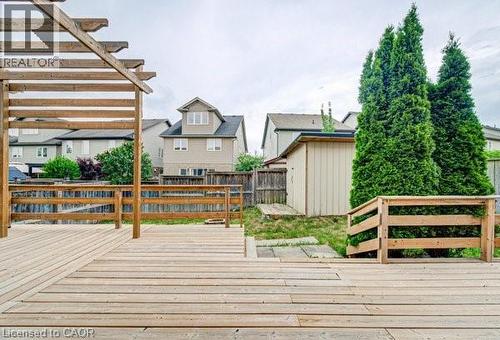 Expansive wood deck with a built-in pergola frame, featuring integrated wood railings and steps leading to the lower lawn area - 55 Isaiah Drive, Kitchener, ON 
