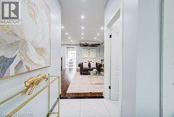White tile flooring entry leading to a living space with wood-finish flooring, recessed lighting, and a prominent white interior door with black hardware - 
