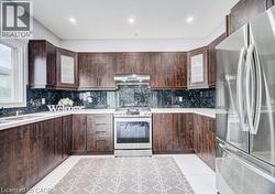U-shaped kitchen featuring dark wood-finish cabinetry, white countertops, and a dark stone backsplash - 