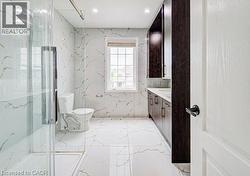 Bathroom featuring a glass-enclosed shower, white tile flooring, white tile walls with gold veining, dark wood-finish cabinetry, and a window providing natural light - 