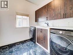 Utility room featuring dark-finish cabinetry, a white countertop, and a white tile backsplash - 