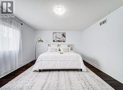 Spacious room featuring dark wood-finish flooring, white walls, and a ceiling-mounted light fixture - 