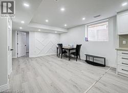 Spacious room featuring light wood-finish flooring, recessed lighting, and a decorative accent wall with geometric paneling - 