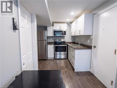 Kitchen featuring white cabinetry, stainless steel appliances, speckled countertops, and wood-finish flooring - 304 Lemon Grass Crescent Unit# B, Kitchener, ON 