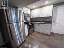 Modern kitchen featuring stainless steel appliances, white cabinetry, wood-finish flooring, recessed lighting, and a dark countertop - 304 Lemon Grass Crescent Unit# B, Kitchener, ON 