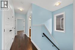 Hallway with dark wood-finish flooring, light blue wall paint, and white trim - 