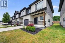 Contemporary townhome exterior featuring vertical and horizontal siding, stone facade accents, a covered front entry, and black-framed windows - 