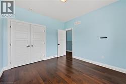 Interior room featuring dark wood-finish flooring, light blue painted walls, and white trim - 