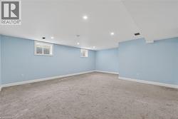 Expansive finished room with light blue walls and gray carpeting - 