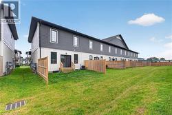 Rear exterior featuring dark siding, white lower siding, wood fences, and a grass lawn - 
