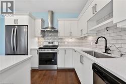 Kitchen featuring white cabinetry with silver hardware, white countertops, and wood-finish flooring - 