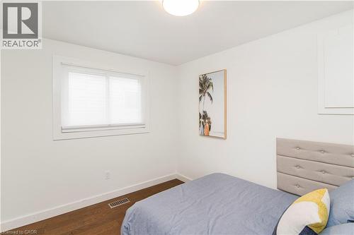 Bedroom featuring wood-finish flooring, white baseboards, a single window with blinds, and white painted walls - 39 Forestgate Drive, Hamilton, ON 