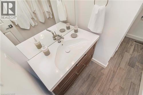 Bathroom vanity featuring a white countertop with an integrated sink, polished chrome faucet, and wood-finish cabinetry - 39 Forestgate Drive, Hamilton, ON 